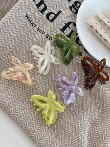 Detail view of colorful butterfly hair claws in acetate finish on textured fabric