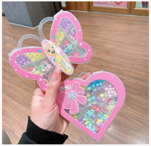 Dettaglio delle scatole a farfalla e cuore piene di perline colorate per gioielli fai-da-te