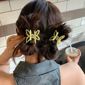 Elegant butterfly acetate hair claws in pastel colors on a model's braided hairstyle