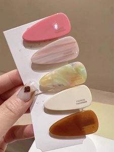 Détail de cinq barrettes à cheveux en acétate fait main aux motifs marbrés