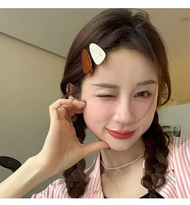 Détail de barrettes goutte en acétate blanc et caramel portées sur les cheveux latéraux