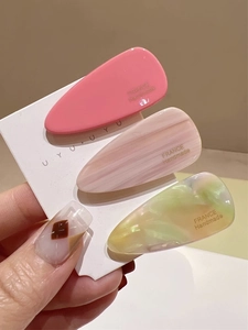 Détail de trois barrettes goutte d'eau en acétate avec motifs marbrés en gros plan