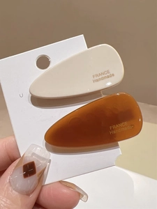 Détail de pinces à cheveux en acétate crème et ambre avec inscription faite à la main