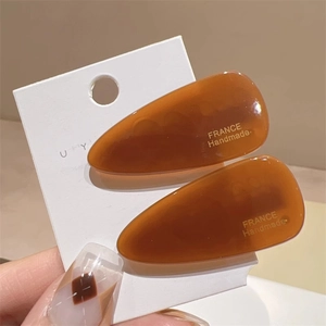 Détail de barrettes goutte en acétate ambré avec inscription dorée France Handmade