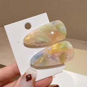 Détail de deux barrettes à cheveux en acétate colorées à la main avec motifs pastels