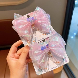 Détail de pinces à cheveux nœud sirène rose avec perles et paillettes sur carte artisanale