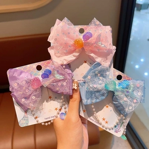Détail de pinces à cheveux sirène avec nœuds, perles et dentelle pour petites filles