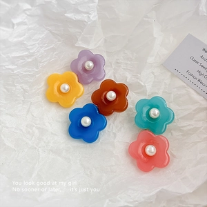 Six barrettes à fleurs en résine colorée avec perles centrales sur papier texturé