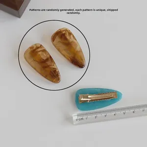 Detail showing 5.5cm resin hair clips with amber texture and gold metal duckbill base