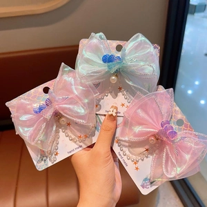 Détail de barrettes nœuds sirène irisées faites main avec perles et breloques coquillages
