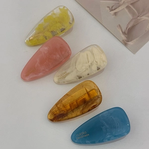 Flat lay of colorful teardrop hair clips in yellow, pink, amber and blue acetate
