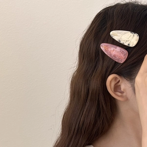 Water-drop hair clips in beige floral and pink marble resin on long wavy brown hair