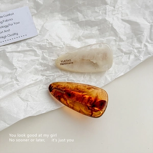 Detailed view of handmade marble and amber acetate hair clips with YLETAO branding