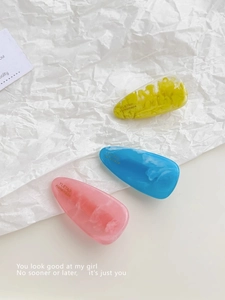 Detailed macro of yellow, blue and pink water-drop hair clips with marble resin texture