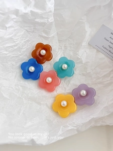 Détail de barrettes fleurs en résine pastel avec perles centrales en six couleurs variées