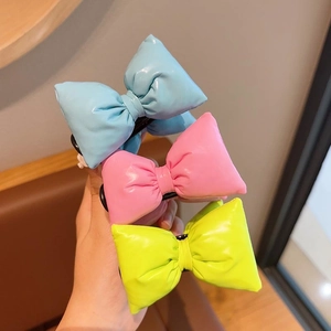 Detailed close-up of shiny puffy bow hair clips in blue, pink, and vibrant green