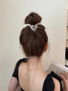 Close-up of heart-shaped metal hair tie with brushed silver finish on elegant hairstyle