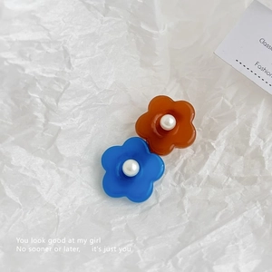 Détail de barrettes fleurs en résine bleues et oranges avec perles sur papier texturé
