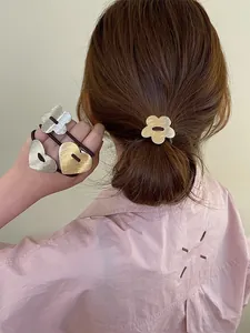 Detailed view of brushed metal flower and heart charms on elastic hair ties
