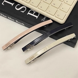 Detailed close-up of acetate hair clips in three colors with metal alligator backs