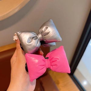 Detail of 3D metallic silver and rose pink bow hair clips with glossy finish texture