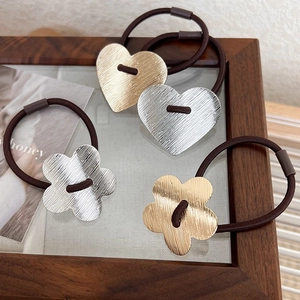 Detailed close-up of four brushed metal heart and flower hair ties in gold and silver