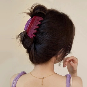 Detail of rose red marbled acetate hair claw clip worn by a model in a minimalist style