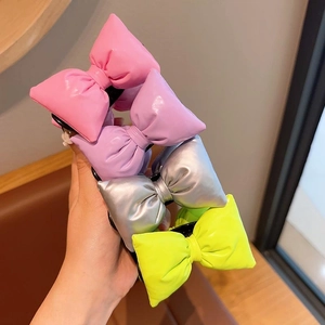 Detailed close-up of colorful glossy 3D bow hair clips in pink, purple, silver and green
