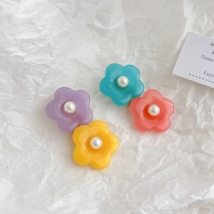 Lot de quatre barrettes à fleurs colorées en résine avec perles sur fond blanc texturé