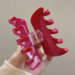 Detailed macro view of the rose red marbled texture and golden spring of the hair claw clip