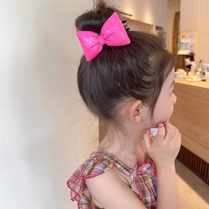 Charming bright pink bow hair clip for girls shown on an elegant bun hairstyle