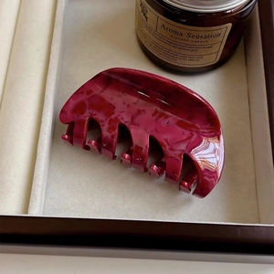 Detailed top view of a large acetate claw clip with deep red marble texture on a tray