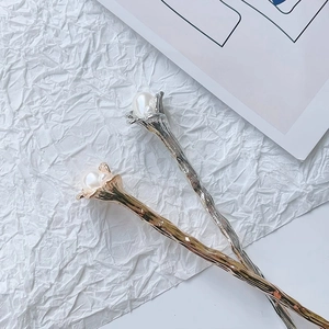 Close-up of elegant gold and silver metal flower hair sticks with white pearls