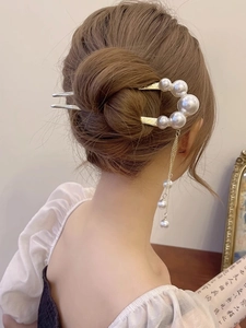 Close-up of pearl tassel U-shaped hair pin in a sophisticated bun hairstyle