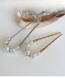 Detailed close-up of U-shaped hairpins with pearls and engraved vintage metal patterns