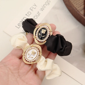 Close-up of satin scrunchies with golden rose metal charms and pearl embellishments