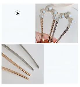 Detail of metal U-shaped hair pin with elegant pearl accents and vintage relief patterns