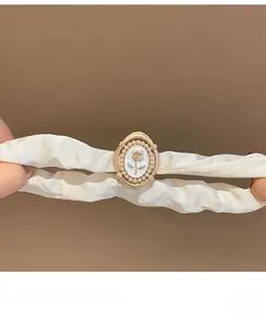 Detail of cream satin hair scrunchie with vintage rose pearl centerpiece and high elasticity