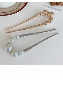 Detailed view of U-shaped hairpins with pearls and engraved vintage scroll patterns