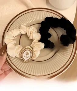 Close-up of vintage satin hair scrunchies with pearl rose gold buckles in cream and black