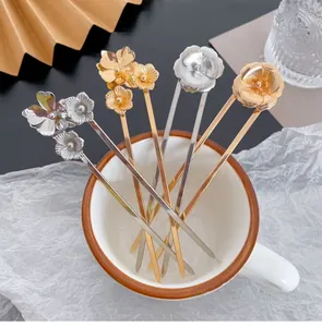 Detail of four gold and silver vintage floral hairpins styled in a white ceramic cup