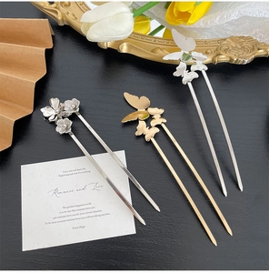 Detailed view of metal butterfly and flower hair pins set on elegant vanity background