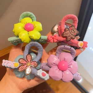 Close-up of four colorful knitted hair clips with 3D floral and bear decorations