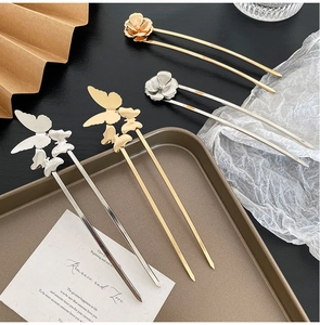 Detail of vintage style U-shaped hair fork with metallic flower and butterfly motifs