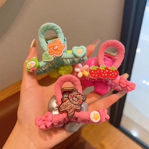 Detail of plush floral hair claws with colorful cartoon bears and strawberry charms