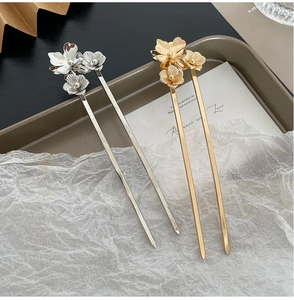 Detailed close-up of gold and silver floral hair pins on an elegant display tray