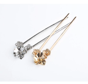 Detail of vintage metal hair pins with gold and silver flower patterns on white background