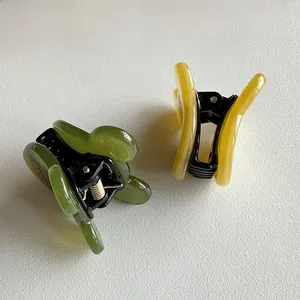 Detail of olive green and yellow acetate hair clips with translucent wavy edges