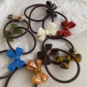 Close-up of high-elasticity hair ties featuring glossy resin bows in assorted colors