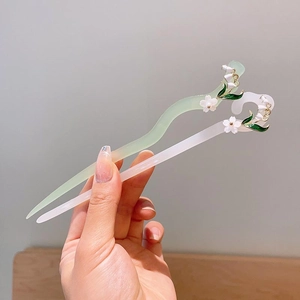 Handheld view of vintage lily of the valley hairpins with acrylic tassels and green leaves